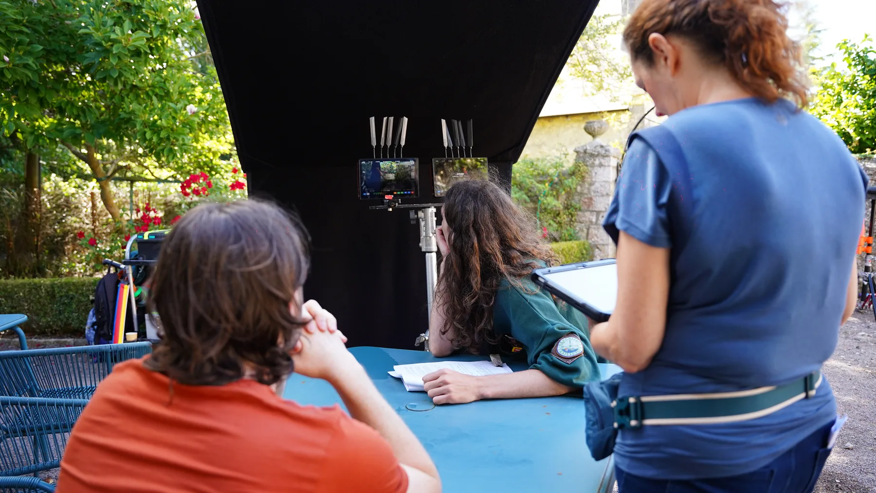 Crew reviewing an outdoor setup beside shaded production monitors