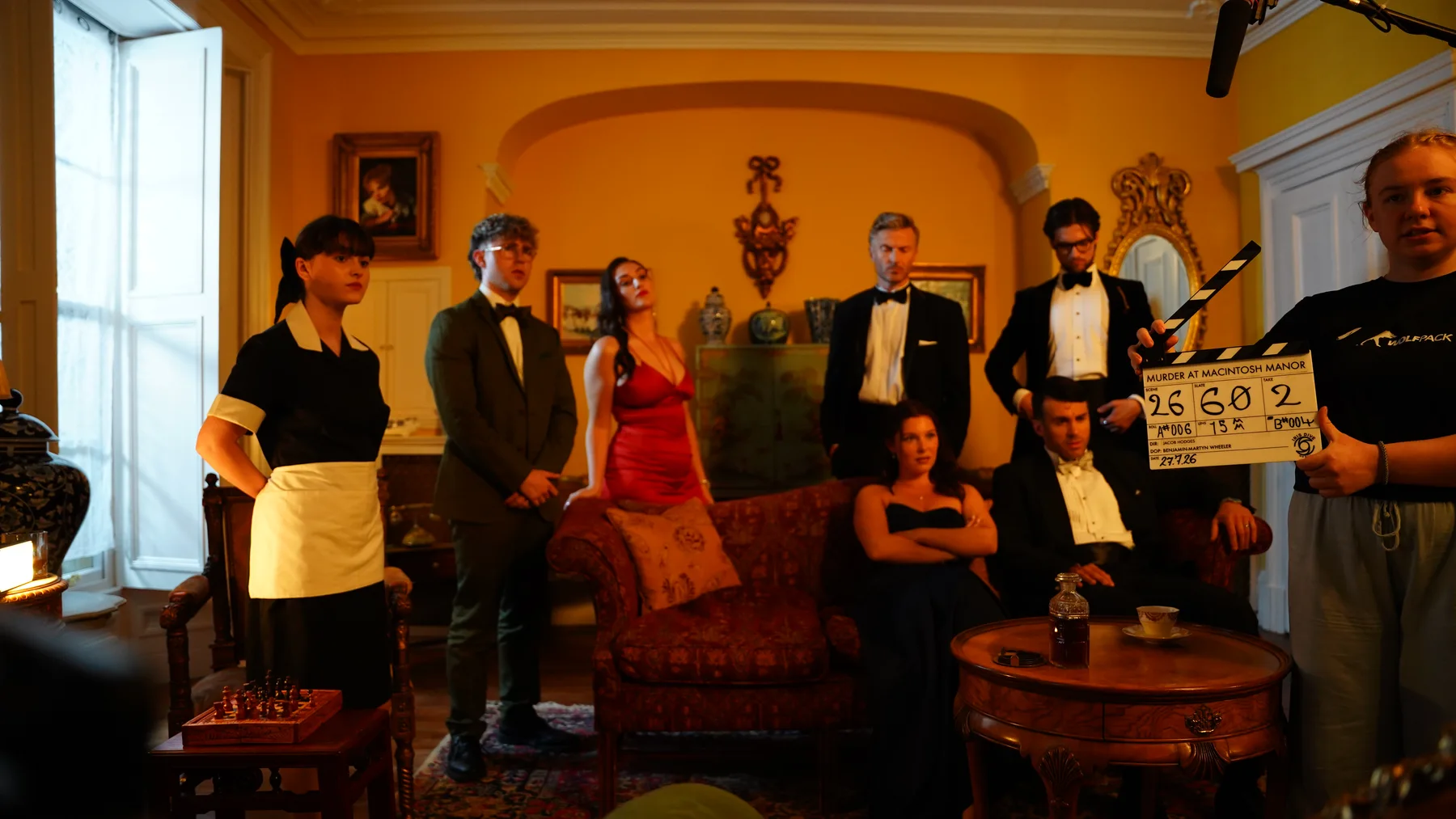 Murder at Macintosh Manor cast and crew preparing a scene with a clapperboard