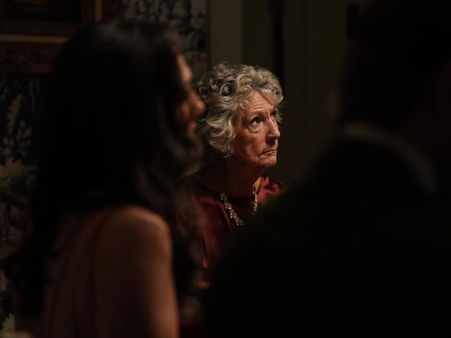 Cast member in burgundy during an interior scene