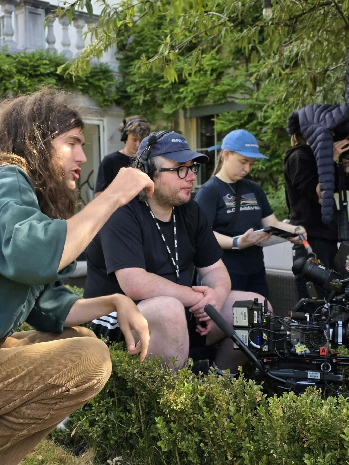 Director and camera crew discussing a shot beside a camera rig in the garden