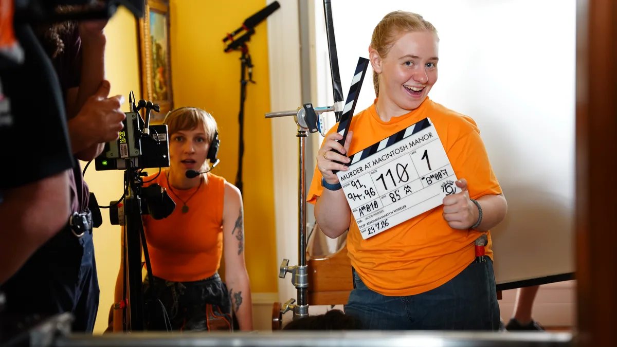 Crew member holding a Murder at Macintosh Manor clapperboard